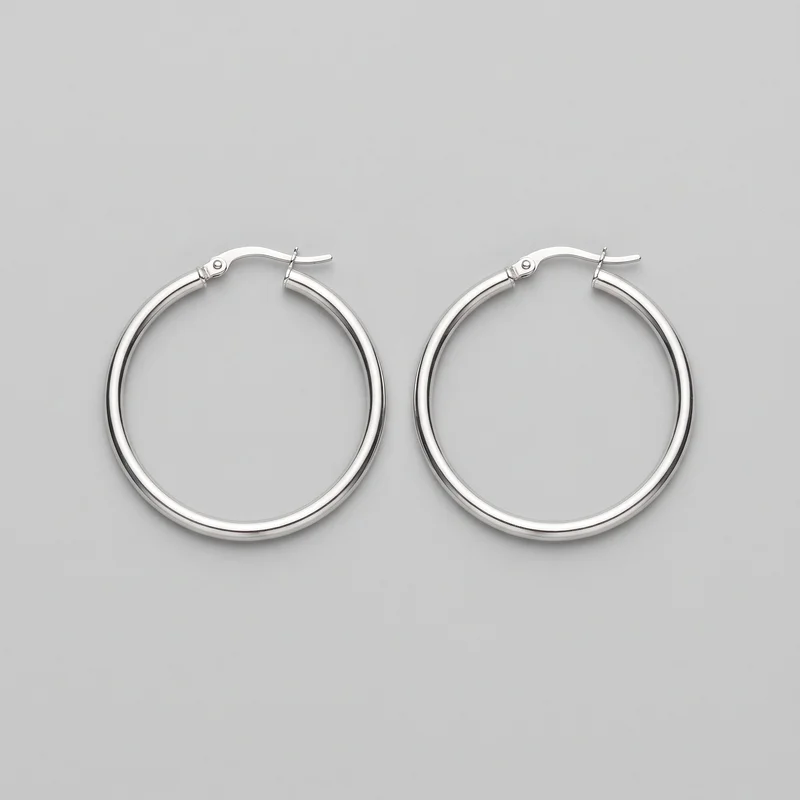 A pair of silver hoop earrings is shown as a standalone product. Both mostly circular tubular hoops have smooth rounded profiles, open gaps at the top, and hinged curved posts with latch closures, small hinge blocks, and connector rings. The polished exteriors are unadorned.
