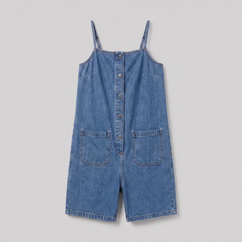 A complete front view of a sleeveless denim playsuit laid flat. It has narrow shoulder straps, a square neckline, a centered full-length button placket, angled upper-front seam details, visible topstitching, two large lower front patch pockets, and wide short legs with straight hems at the upper to mid-thigh.