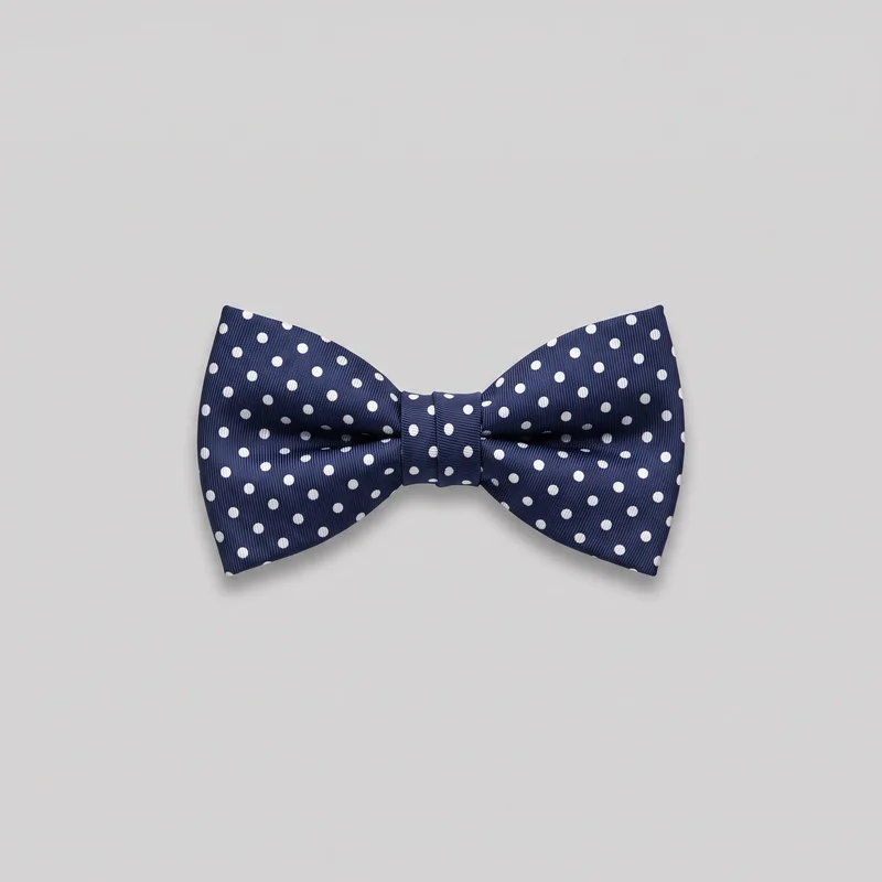 A complete formal bow tie is shown standalone from the front. It has two symmetrical flared folded wings gathered into a narrow central wrap band, with squared outer ends, curved upper inner edges, and soft pleating radiating from the center. Fine diagonal ribbing and an evenly spaced contrasting polka-dot pattern cover both wings and the center band.