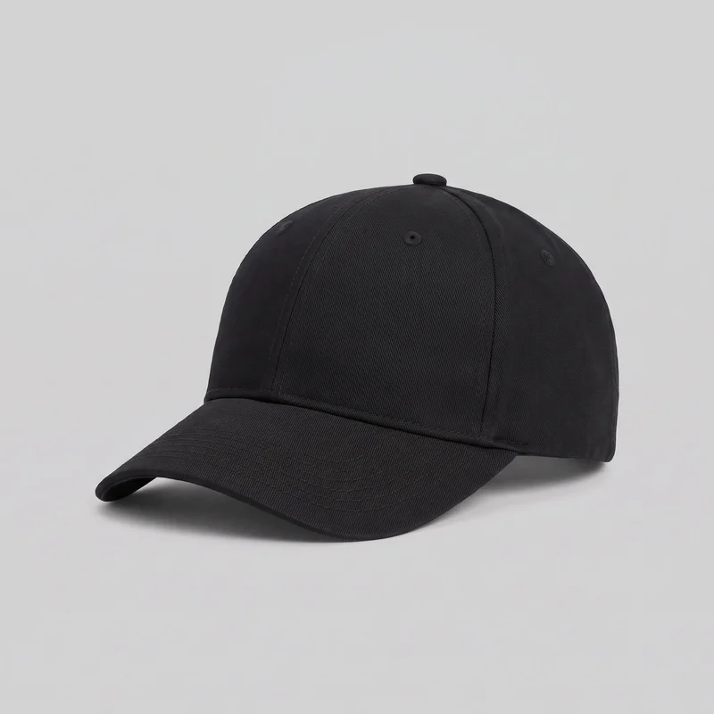 A plain black baseball cap is shown as a standalone product in three-quarter view. It has a structured six-panel domed crown, a curved front visor, raised seams from the visor to the crown, a covered top button, embroidered ventilation eyelets, a seam band above the visor, and multiple rows of stitching across the visor. No logos, prints, patches, embroidery, or other embellishments are visible.