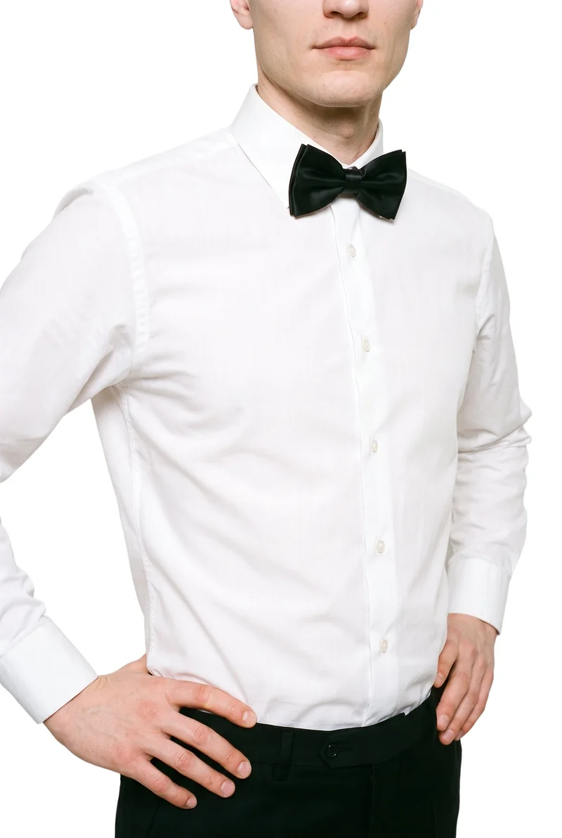 A male model wears a black satin bow tie, shown from an angled front view in a torso crop with his hands on his hips. The product is presented against a pure white backdrop.