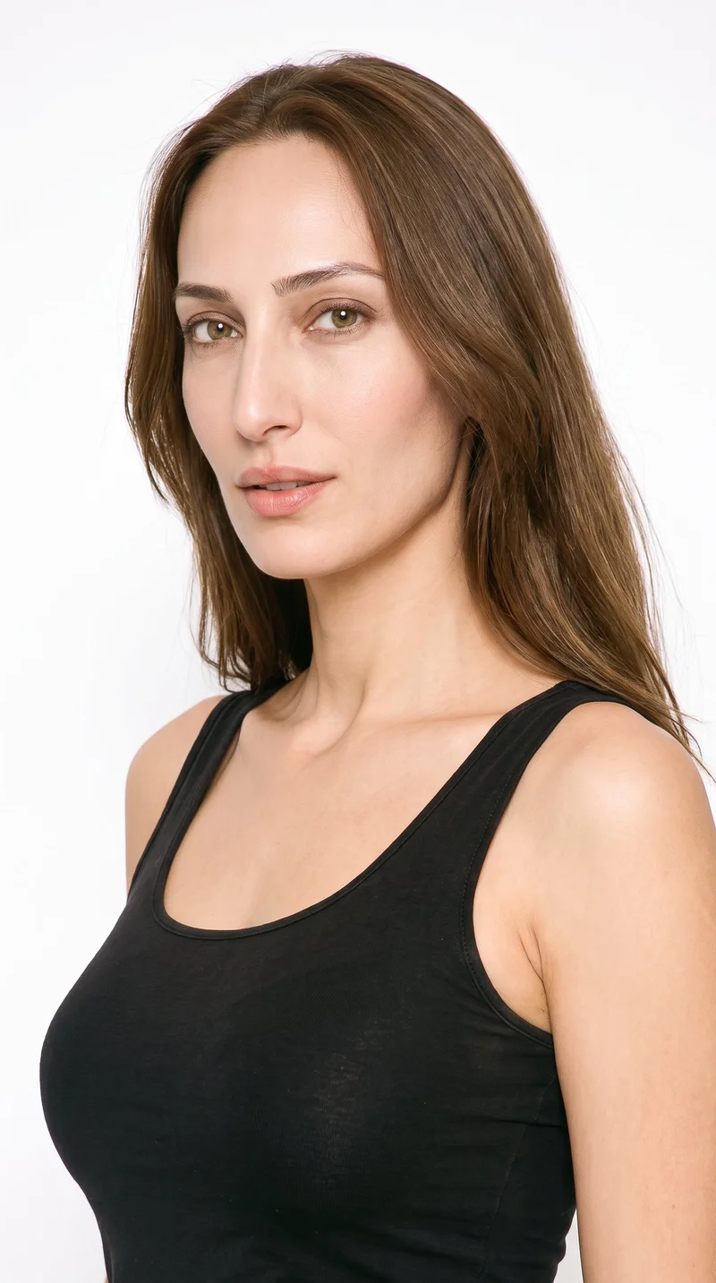 This 36-year-old Turkish woman has a medium skin tone with a warm golden undertone. Her face is long, with more length than width, a tall forehead, and elongated cheeks. She has medium-thickness eyebrows, green eyes, and medium-sized lips. Her brown hair is worn long and loose past the shoulders with natural volume.