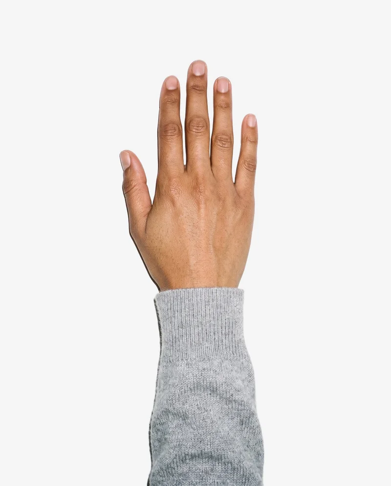 A hand lies flat, shown from above, with the wrist area framed against a cloud-white backdrop.