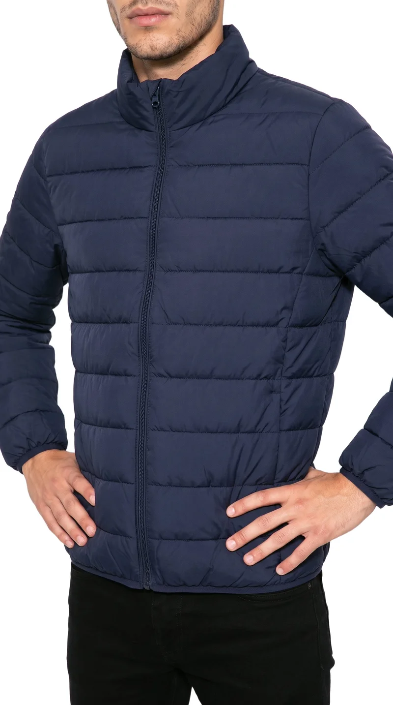 A male model is shown from the torso in an angled front view, wearing a men's navy padded jacket with his hands on his hips. The jacket is presented against a pure white backdrop.