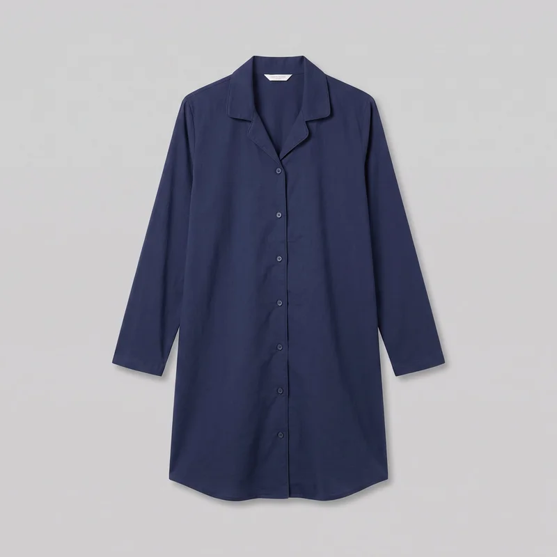 A navy cotton nightshirt is shown in a mostly complete front view against a plain backdrop. It has a relaxed straight silhouette, a notched lapel collar forming a V neckline, long set-in sleeves with plain hems, and a full front button closure with multiple round buttons. The extended shirt-length body ends in a rounded shirttail hem, with no visible exterior pockets or embellishments.