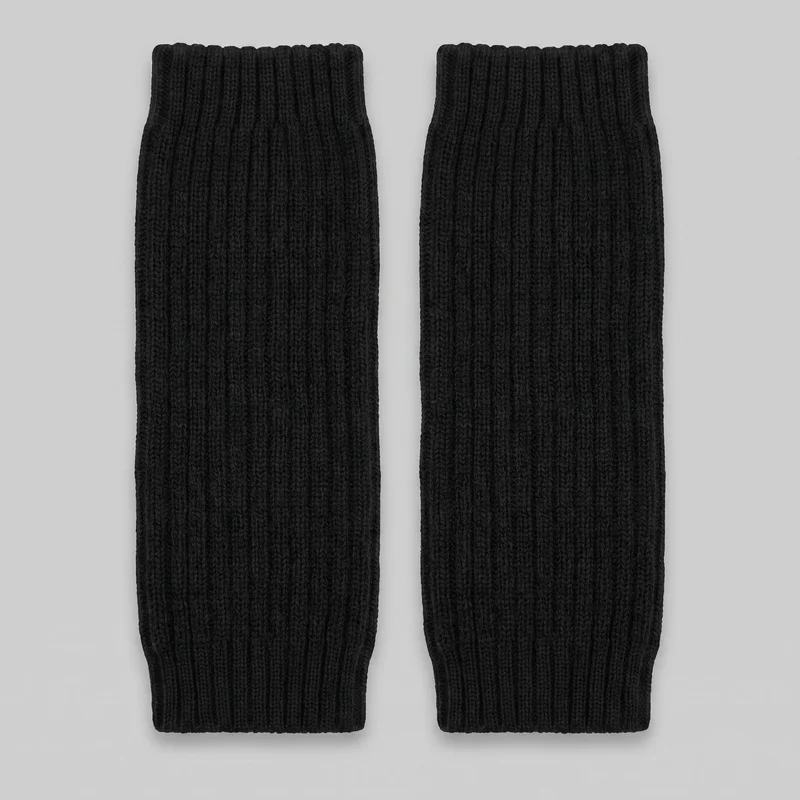 A complete matching pair of black knit leg warmers is shown laid flat side by side. Each tubular warmer has open ends with wide ribbed cuffs, slightly wavy rounded edges, and vertical rib channels running the full length, with no visible closures or embellishments.