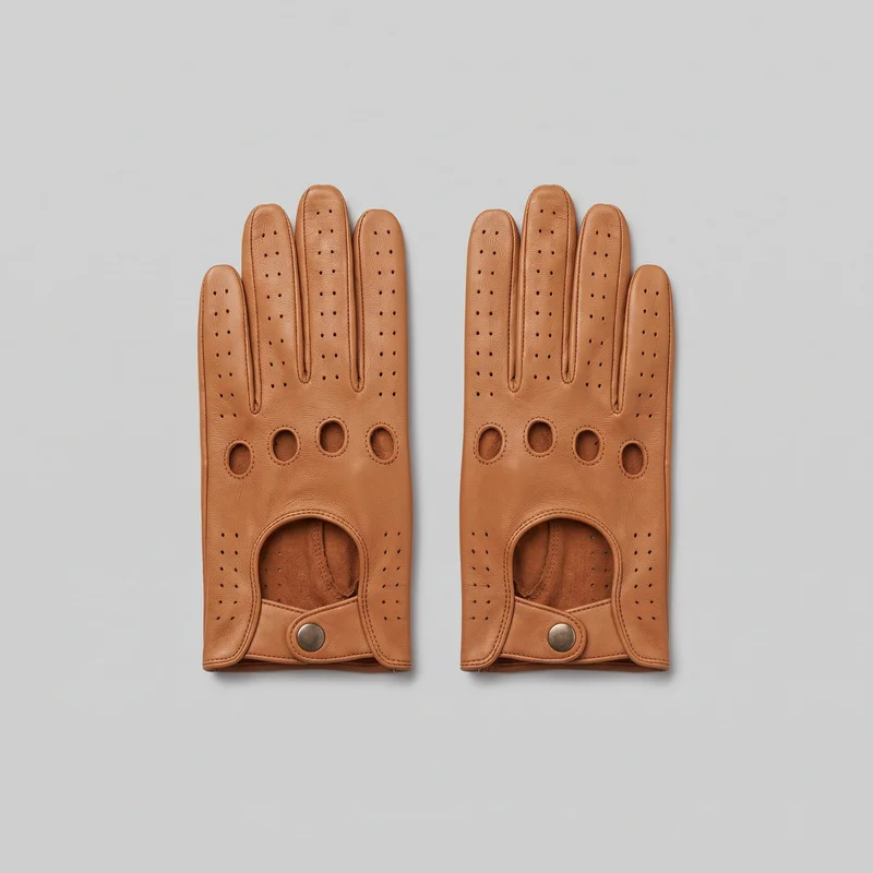 A matching pair of tan full-finger driving gloves lies flat, viewed from the back-of-hand side. The gloves have rounded fingertips, separate finger channels, rows of small ventilation perforations, four oval knuckle cutouts with stitched rims, curved wrist cutouts, piped seams, and short wrist tabs secured with round metal snaps.