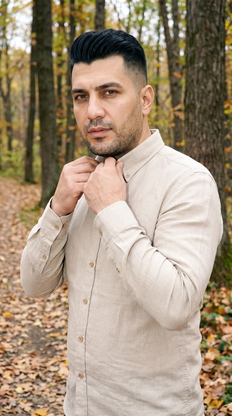 A 46-year-old Turkish man wears a beige linen shirt, shown from the upper body at a front three-quarter angle with his hands on his neck. His confident expression is visible against an autumn forest backdrop.