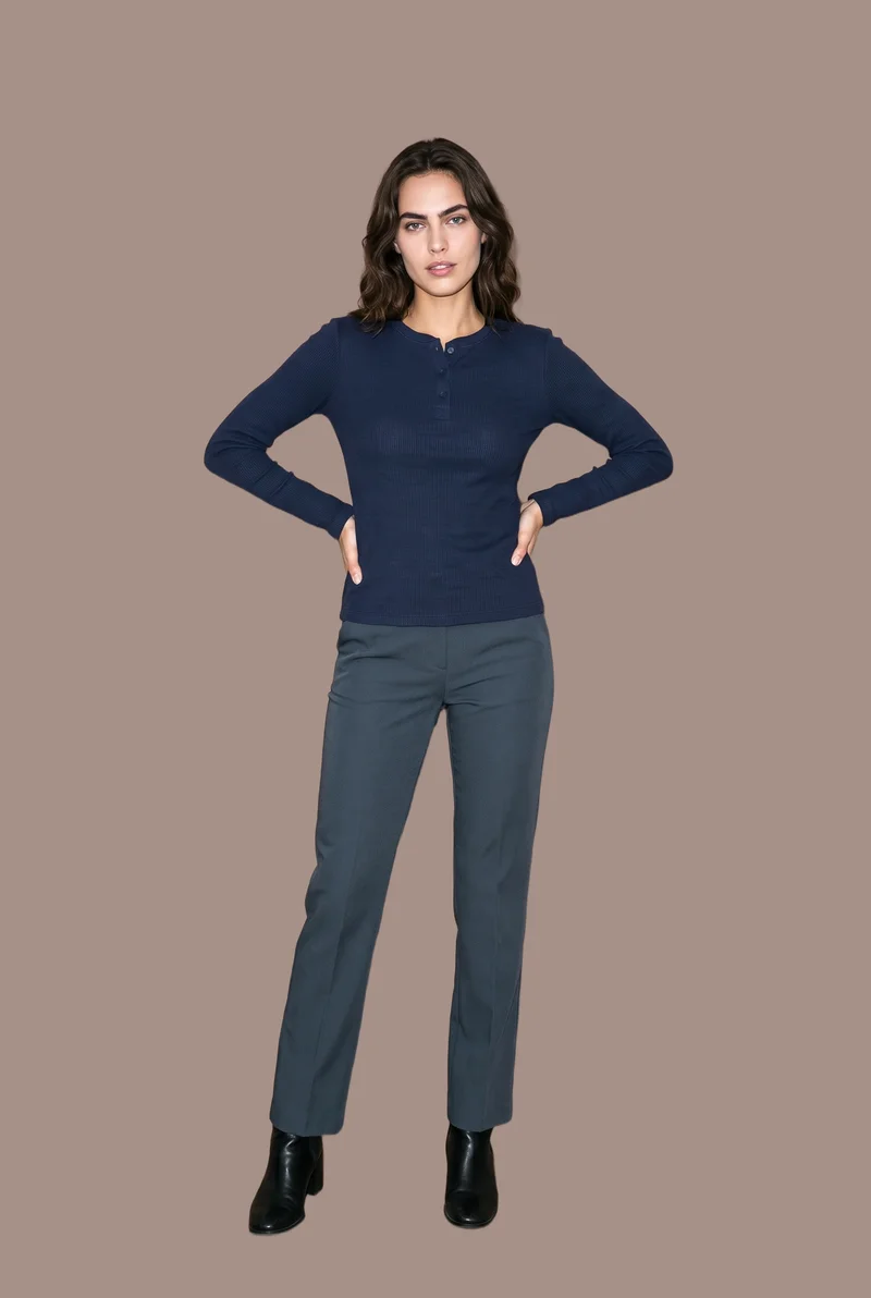 A 22-year-old Caucasian woman wears a women's navy waffle-knit Henley top in a full-body front view. She stands with a wide stance and a natural facial expression against a flat mushroom-colored backdrop.