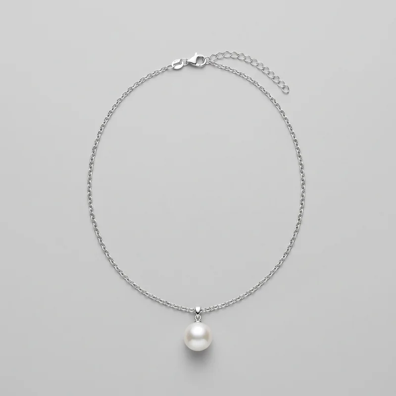 A complete pendant necklace is laid flat, with a fine oval-link chain forming a rounded loop. A single spherical pearl-like drop hangs from a small tapered bail at the bottom center. The lobster clasp, connector rings, and adjustable extender chain with larger open oval links are visible at the top.