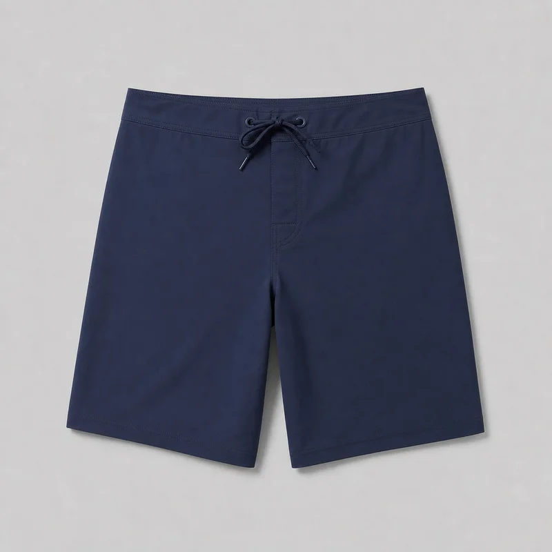 Navy regular-fit board shorts shown mostly complete in a flat front view. They have a low-to-mid rise waistband with multiple rows of topstitching, an integrated lace-up drawstring threaded through reinforced round eyelets, a centered faux fly panel with vertical and curved seam stitching, straight knee-length legs, and double-stitched hems.