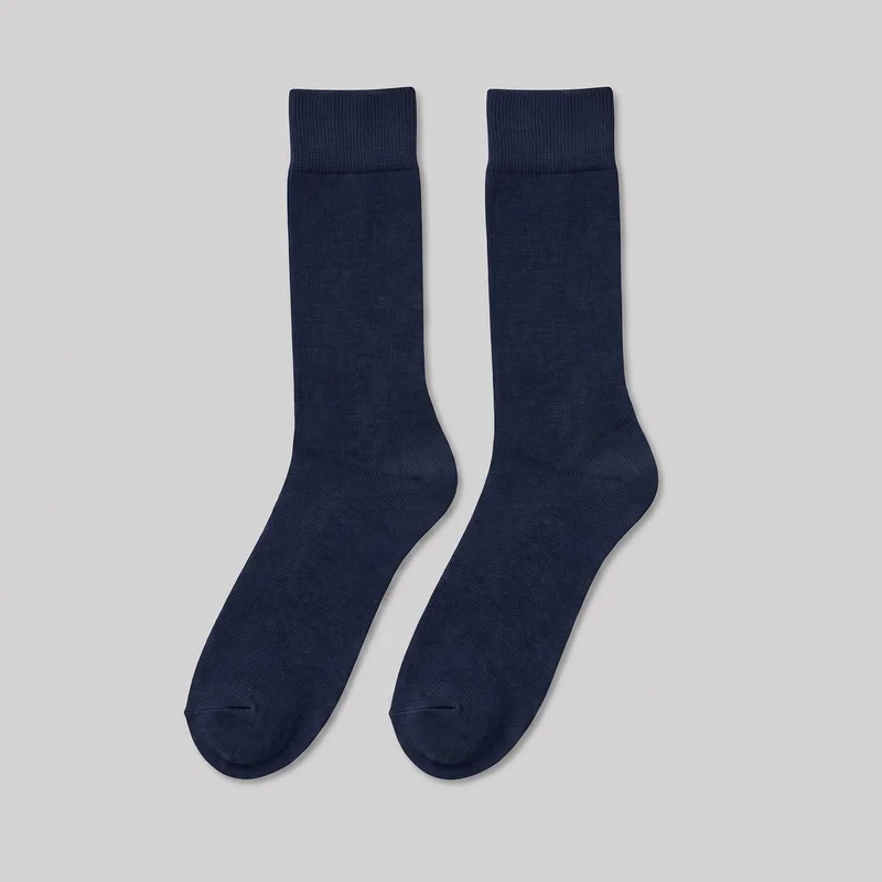 A complete pair of plain navy crew-length socks is laid flat, showing the straight ribbed cuffs, smooth fine-knit legs and feet, shaped heel turns, and rounded toes with visible reinforced toe seams. The socks have a slim tubular silhouette and no visible logos, prints, closures, pockets, patches, embroidery, or embellishments.