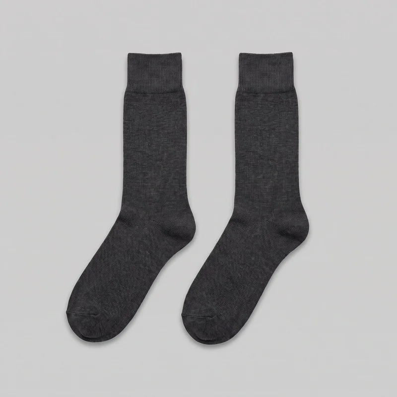 A matched pair of charcoal formal crew socks is laid flat side by side as a standalone product. The socks have wide ribbed cuffs, straight tubular legs, finer plain-knit sections, shaped heels, rounded closed toes, and visible seams across the toes.