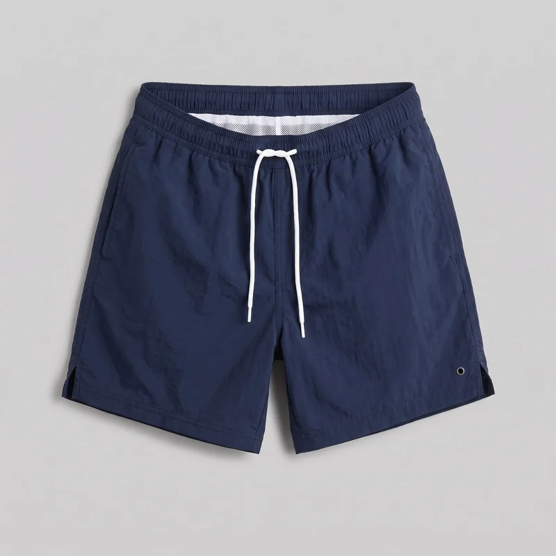 Navy swim shorts laid flat in a mostly complete front view. The shorts have a gathered elastic waistband with an integrated drawcord tied at the center, straight loose legs ending above the knee, side-entry pockets, short side hem vents, double-stitched hems, and a single metal drainage eyelet near the lower outer leg.