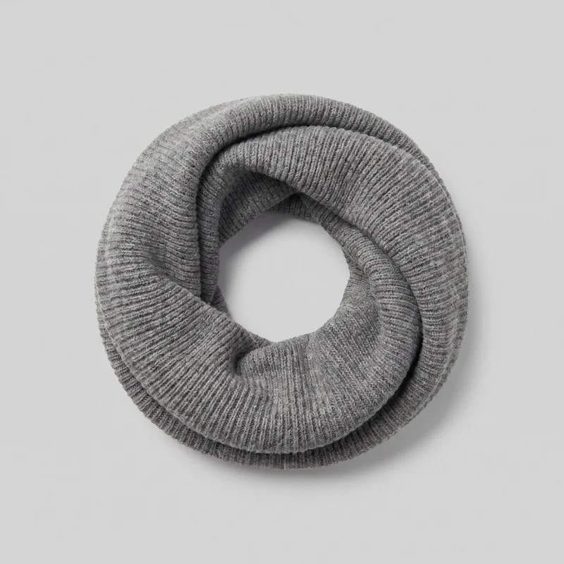 A grey knit snood is shown as a standalone product, coiled into overlapping circular loops with a central opening. Its continuous tubular form has rounded, padded-looking edges, substantial volume, and an all-over ribbed texture with heathered variation. No closures, hardware, logos, prints, patches, embroidery, or embellishments are visible.
