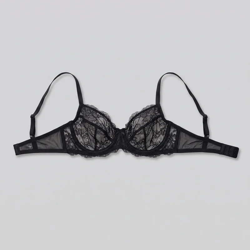 A black women's underwire bra is laid open in a flat standalone view. The full garment is visible, including structured demi cups with seamed panels and sheer floral lace, scalloped trim along the cup edges and lower cradle, a narrow bow-finished center gore, sheer mesh side wings, adjustable shoulder straps with sliders and rings, and a multi-row hook-and-eye back closure.