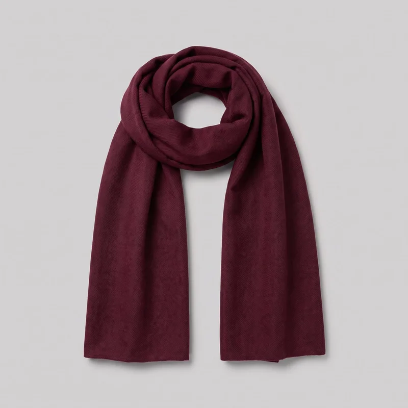 A burgundy wool scarf is shown as a standalone product, arranged in a loop at the top with two straight panels hanging downward. It has a broad, flat shape, plain squared ends, clean unfringed edges, and a softly folded drape through the loop. The woven surface has subtle diagonal texture, with no visible closures, hardware, logos, patterns, patches, embroidery, or embellishments.