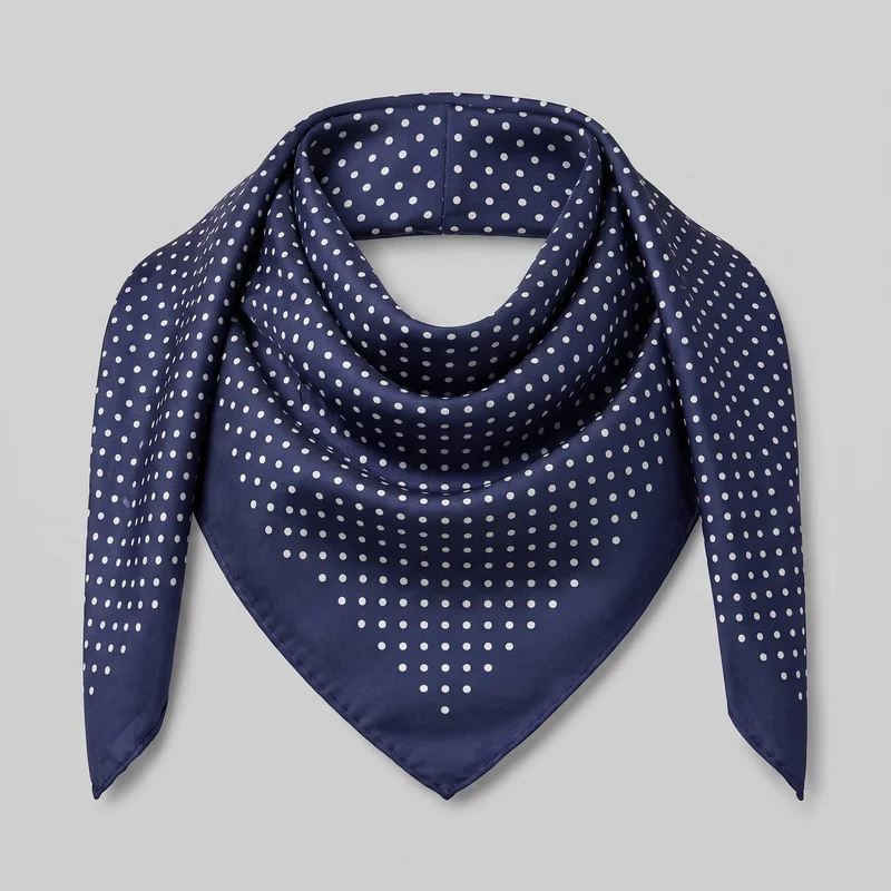 A men's square silk scarf is shown as a standalone product, folded and draped into a loop with a pointed triangular front and two tapered side ends. The visible surface has an evenly spaced all-over dot print, soft folds around the upper opening, and finished stitched edges. No logos, patches, embroidery, or other embellishments are visible.