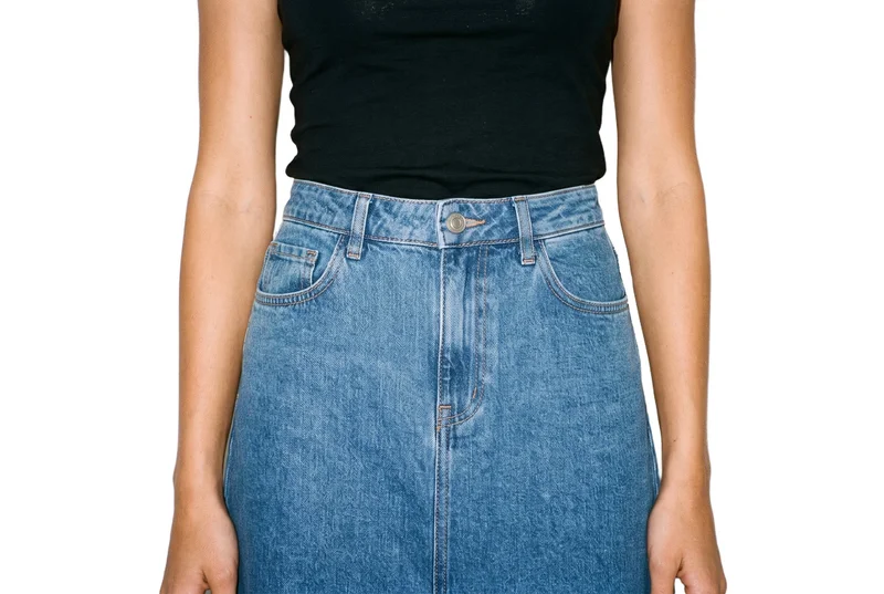 A denim A-line skirt shown from the front, framed from the hips with the hips level. The skirt is presented against a pure white backdrop.