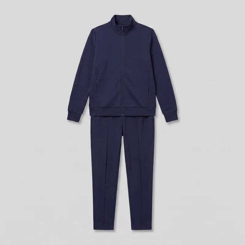 A complete navy tracksuit set is laid flat in a front view, showing a regular-fit zip-front jacket with a high stand collar, long sleeves, banded cuffs, a straight banded hem, and a center zipper extending from the hem to the collar. The jacket also has vertical front seam lines and two zippered side pockets. Matching full-length tapered pants are visible underneath, with vertical front crease or seam lines, side pocket openings near the hips, and plain hems. No logos, prints, patches, embroidery, or embellishments are visible.