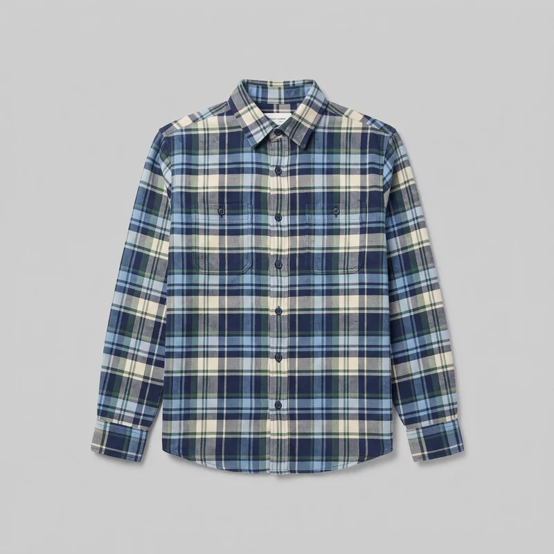 A mostly complete front view of a blue tartan flannel shirt with long sleeves, a pointed fold-down collar, and a full button placket. The regular-fit shirt has two buttoned chest patch pockets, button cuffs, and a curved shirttail hem, with the plaid pattern aligned across the body, sleeves, collar, placket, pockets, and cuffs.