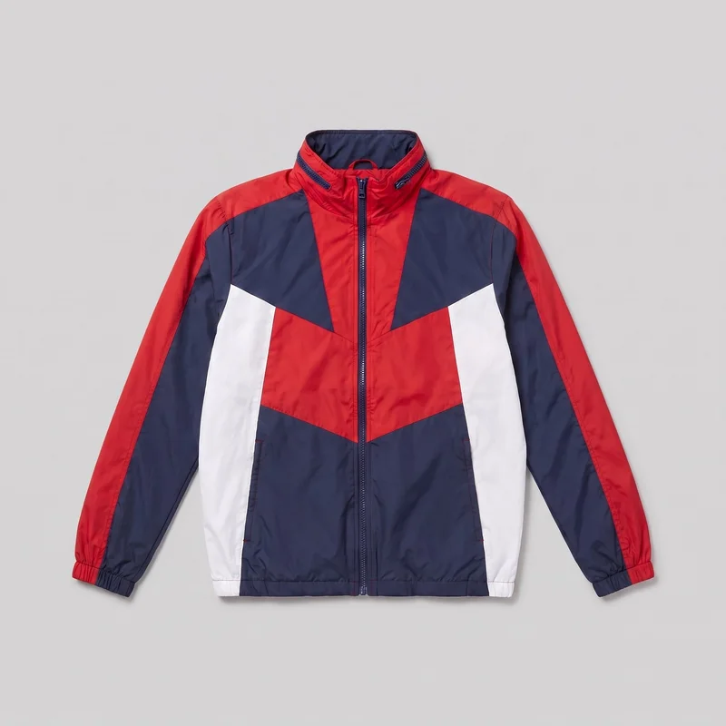 A mostly complete front view of a men's red colour-block windbreaker jacket laid flat against a plain backdrop. The regular-fit jacket has a full-length front zipper, stand collar, long sleeves with gathered elastic cuffs, straight body and hem, angled chest panels, vertical side-body panels, contrasting sleeve sections, and two low vertical welt-style front pockets. Zipper details are visible near both sides of the collar, with no visible logos or other embellishments.