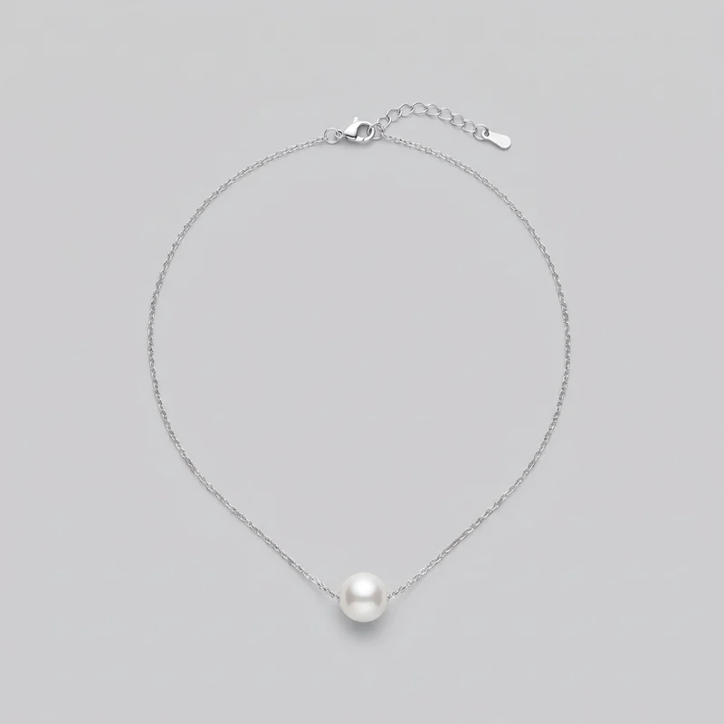 A women's pendant necklace is laid in an oval loop, showing an oval-link chain with a single smooth round bead threaded at the center front. The lobster-claw clasp, adjustable extender chain, and flat rounded end tag are visible; no logos or additional embellishments are shown.