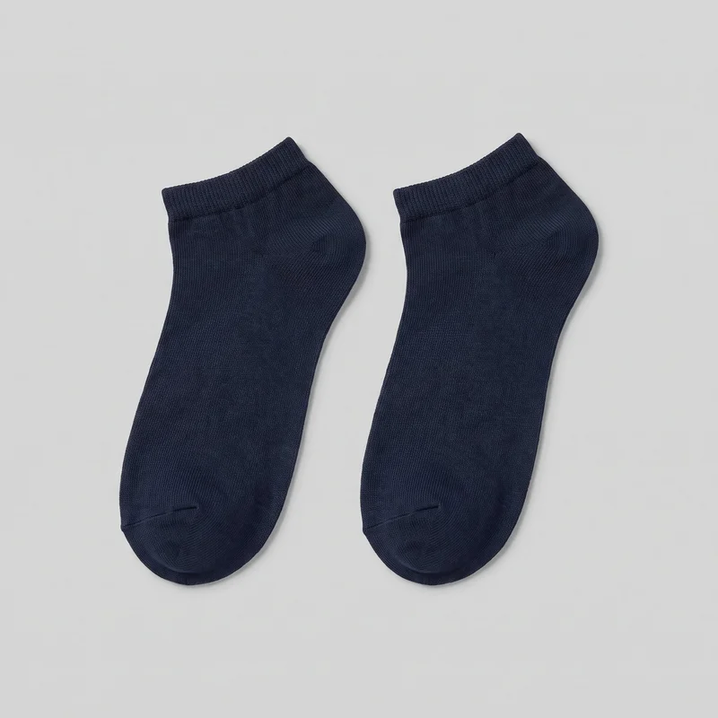 A complete pair of navy low-cut ankle socks is shown laid flat. Both socks have rounded closed toes, shaped heel pockets, smooth fine-knit bodies, and short ribbed cuffs with visible vertical texture at the openings.