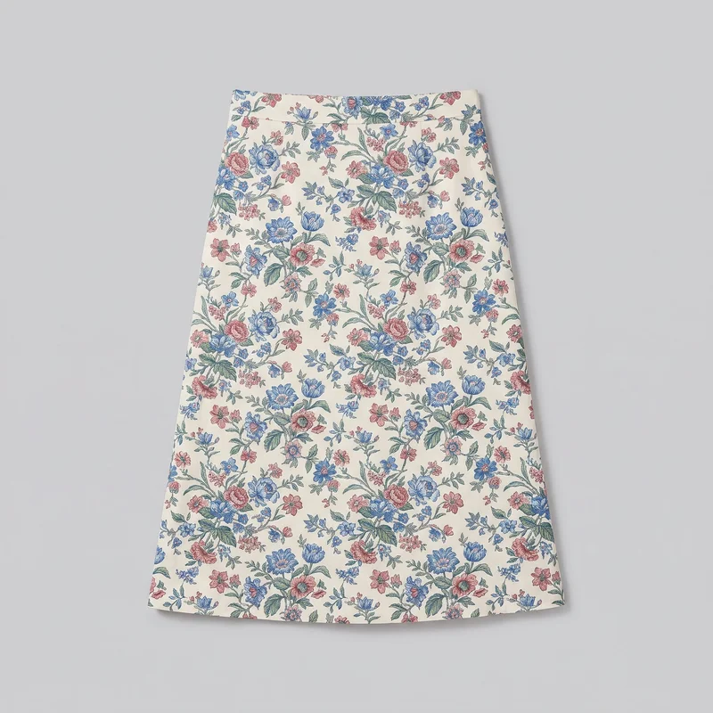 A standalone view shows a full women's A-line midi skirt from its wide straight waistband to its straight lower hem. The skirt is fitted at the waist and flares through the body, with a horizontal seam joining the waistband to the skirt and clean side edges. An all-over botanical floral print of repeated stems, leaves, and varied flower heads covers the waistband and skirt body; no pockets, closure, logos, patches, or embellishments are visible.