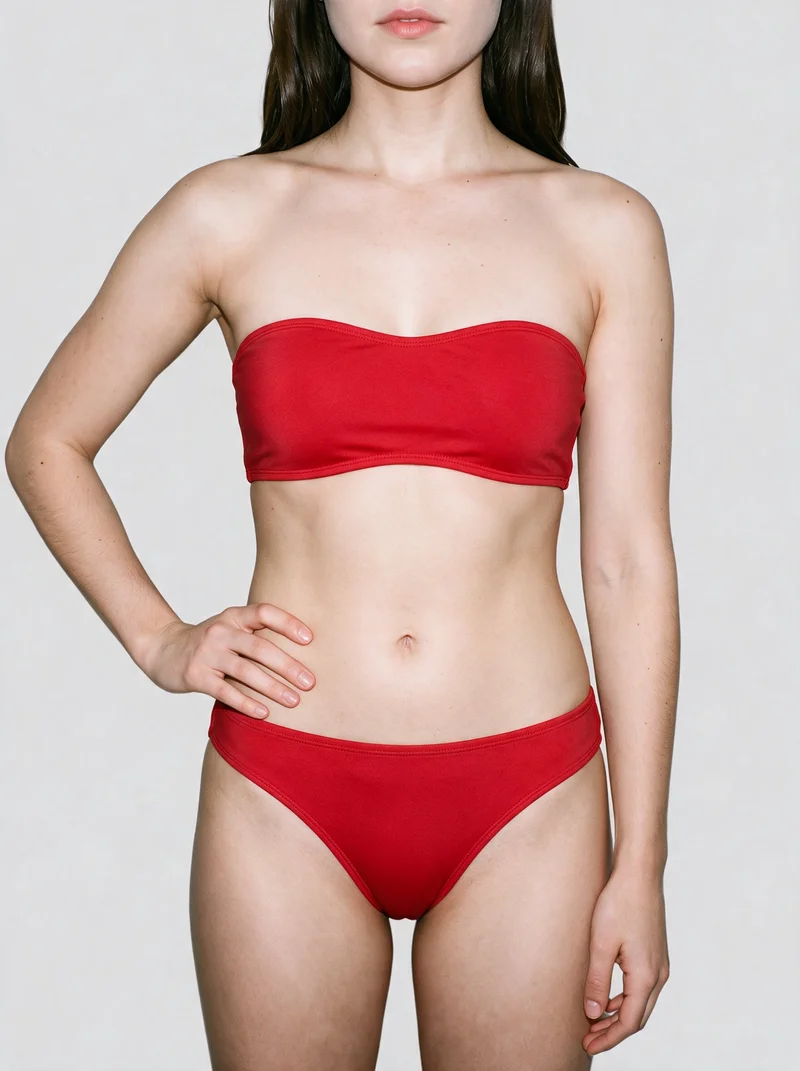 A model wearing a red bandeau bikini is shown from the front in a torso-length frame, with one hand on her hip. The image uses a flat fog grey backdrop.