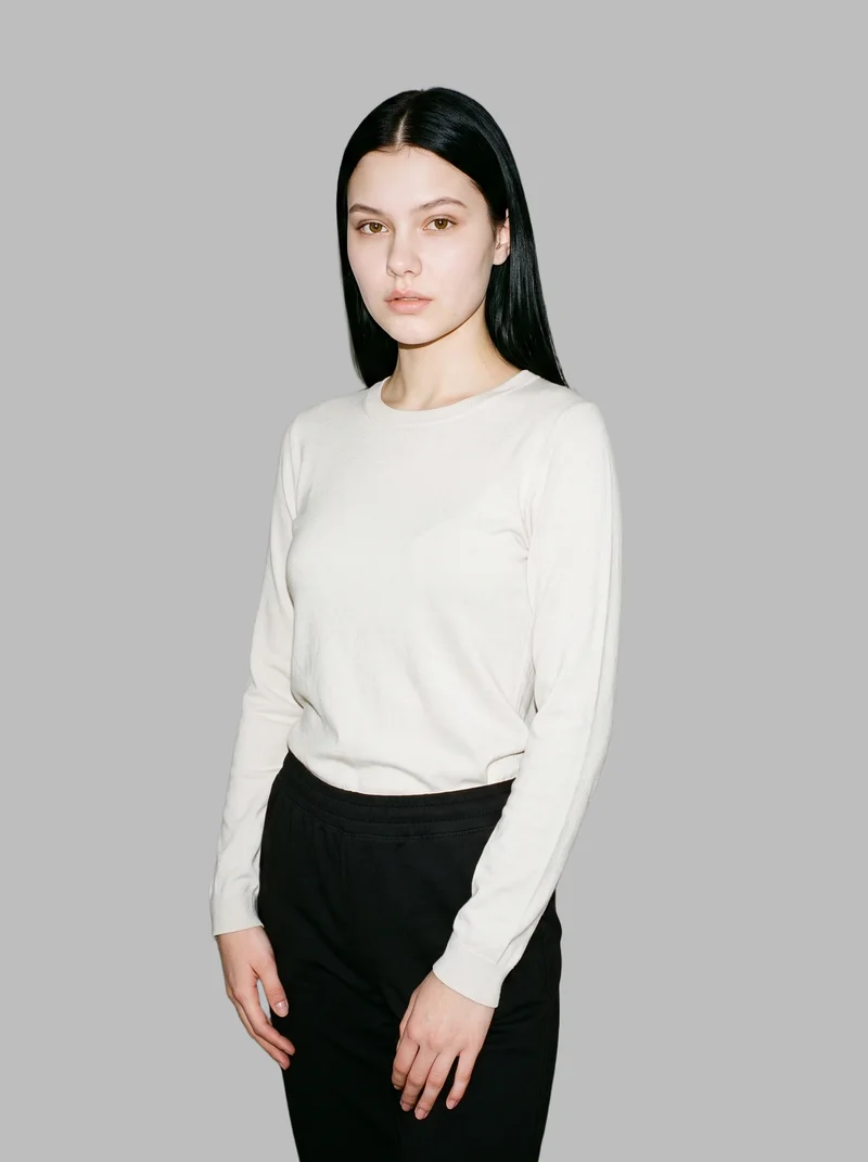 A 19-year-old Caucasian female model wears women's black joggers in a three-quarter-length view from a front three-quarter angle. Her hands are positioned in front and her expression is neutral, with a dove grey flat-color backdrop.