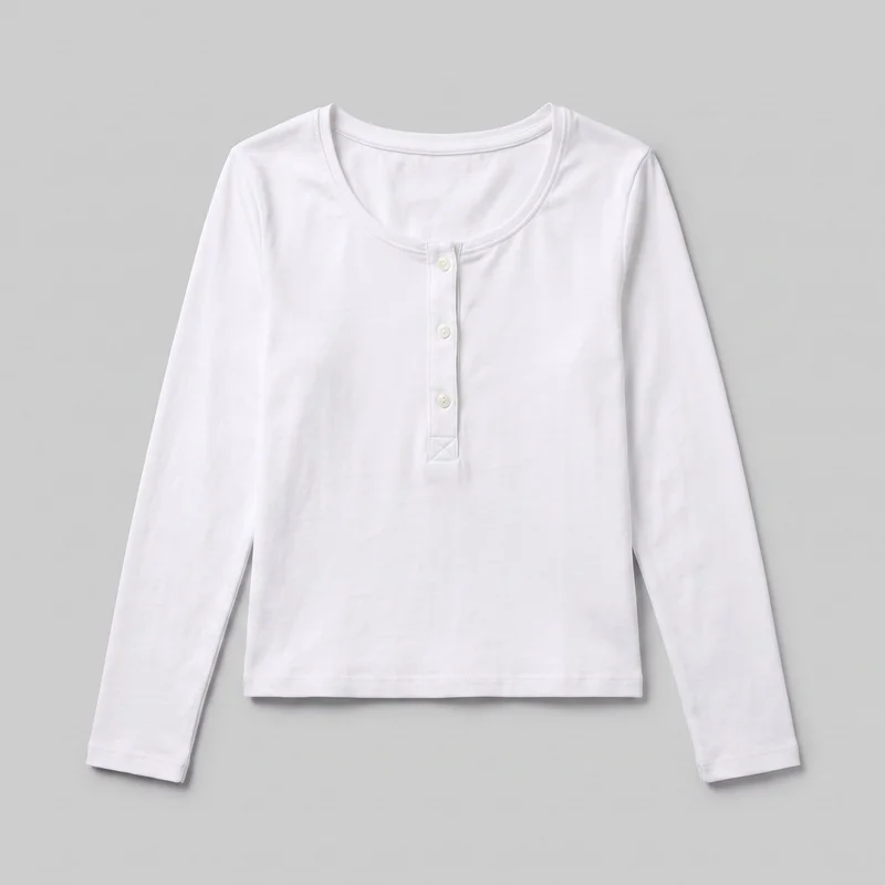 A mostly complete front view of a white long-sleeve henley top laid flat against a backdrop. It has a rounded scoop neckline with narrow binding, set-in shoulders, full-length sleeves, a straight silhouette, and a straight lower hem. A short centered button placket with three visible buttons and a reinforced triangular seam detail is shown at the front.
