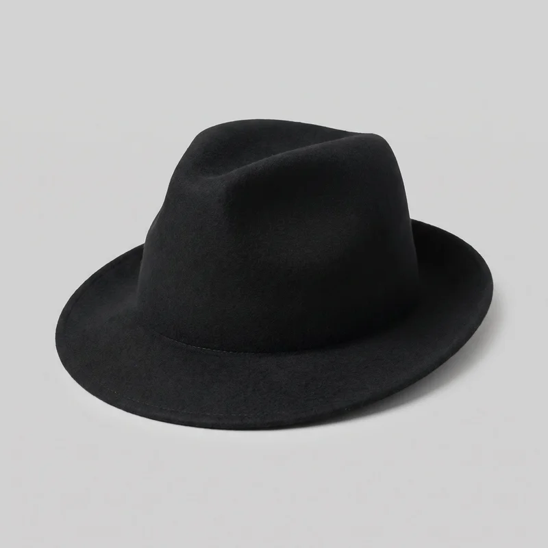 A standalone black wool fedora is shown from a front three-quarter angle. The hat has a structured pinched crown with a center dent and a continuous brim that curves gently downward at the front and sides. Its smooth exterior is unadorned, with a subtle seam or stitched edge around the brim and no visible band, logo, print, embroidery, or other embellishment.