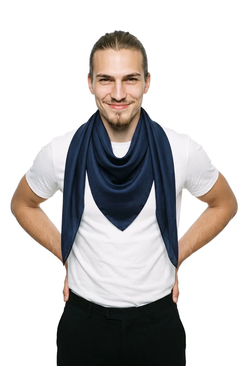 A 20-year-old Caucasian man is shown from the upper body in a front view, wearing a men's navy silk scarf with his hands on his hips and a natural expression. The image uses a pure white backdrop.
