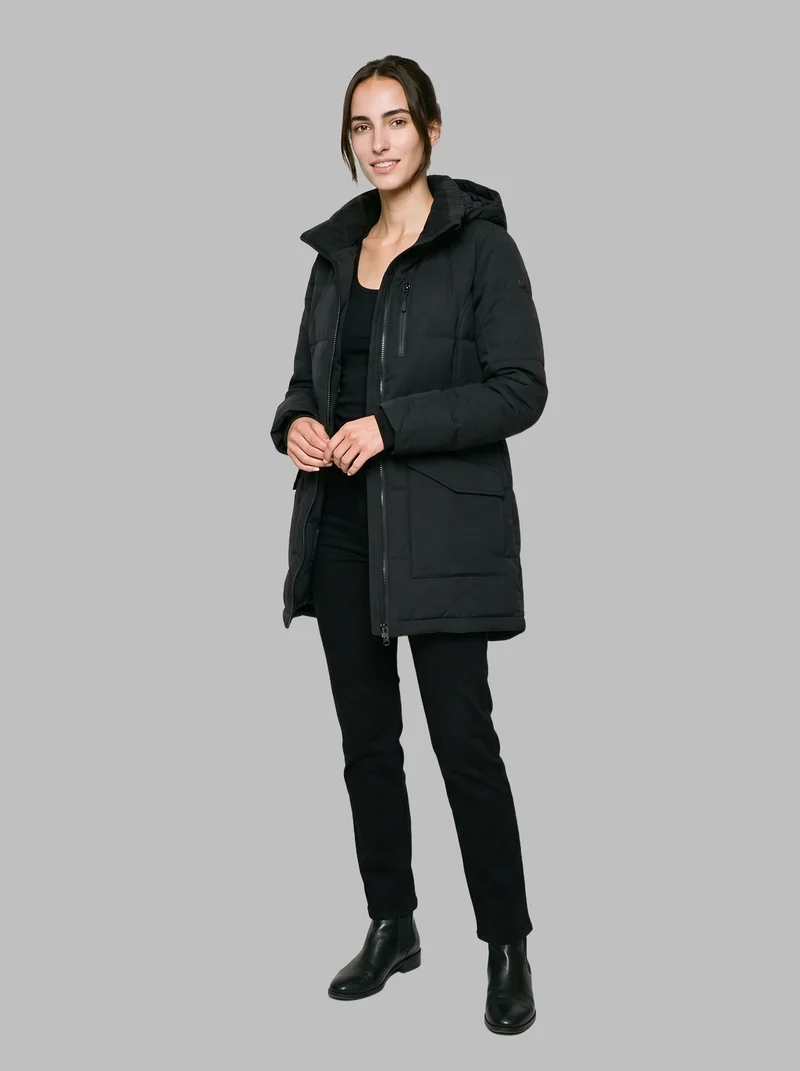 A 20-year-old Caucasian woman wears a black parka, shown full body from an angled front view with her hands held in front. She is smiling against a flat Silver Mist backdrop.