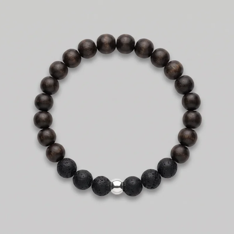 A complete closed circular bracelet is shown flat against an unspecified backdrop. Smooth, grain-textured round beads form most of the upper arc, while pitted, porous-textured beads are grouped along the lower front, with one polished reflective spherical bead centered at the bottom.
