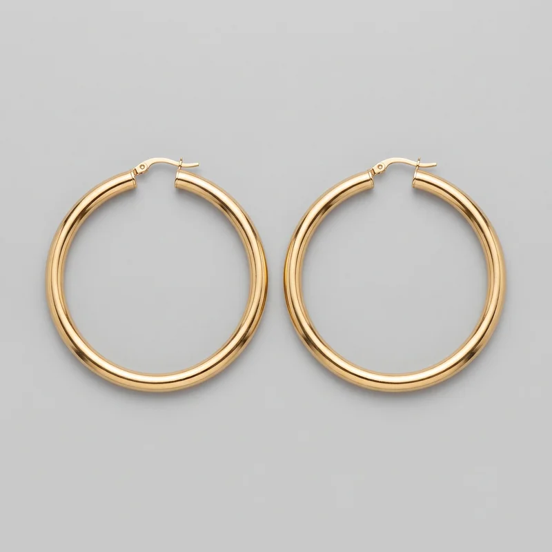 A matching pair of large gold hoop earrings is shown side by side against a standalone product backdrop. Each earring has a circular open-hoop shape, smooth rounded tubular construction, and a hinged latch-back closure visible at the top, including a small pivot rivet, curved lever arm, and straight post crossing into the opposite tube end.