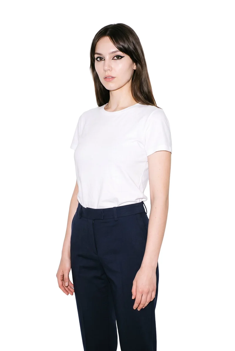 A 20-year-old Slavic woman wears women's navy wool suit trousers, shown standing straight in a three-quarter-length angled front view with a neutral expression. The trousers are presented against a pure white backdrop.