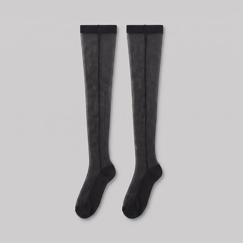 A complete pair of thigh-high stockings is laid flat, showing the wide upper bands, long semi-transparent leg sections, darker vertical seam-like lines, and closed feet. The bands, heels, soles, and toe areas are opaque, with small visible seams at the closed toes; no logos, prints, patches, embroidery, or embellishments are visible.