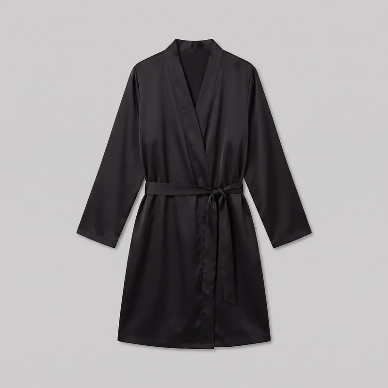 A mostly complete front view of a women's black satin wrap robe laid flat against a backdrop. It has a V-shaped crossover front, shawl-style banded neckline, dropped shoulders, full-length wide sleeves, a straight lower hem, stitched edging, and an integrated waist tie knotted at one side with two hanging ends.