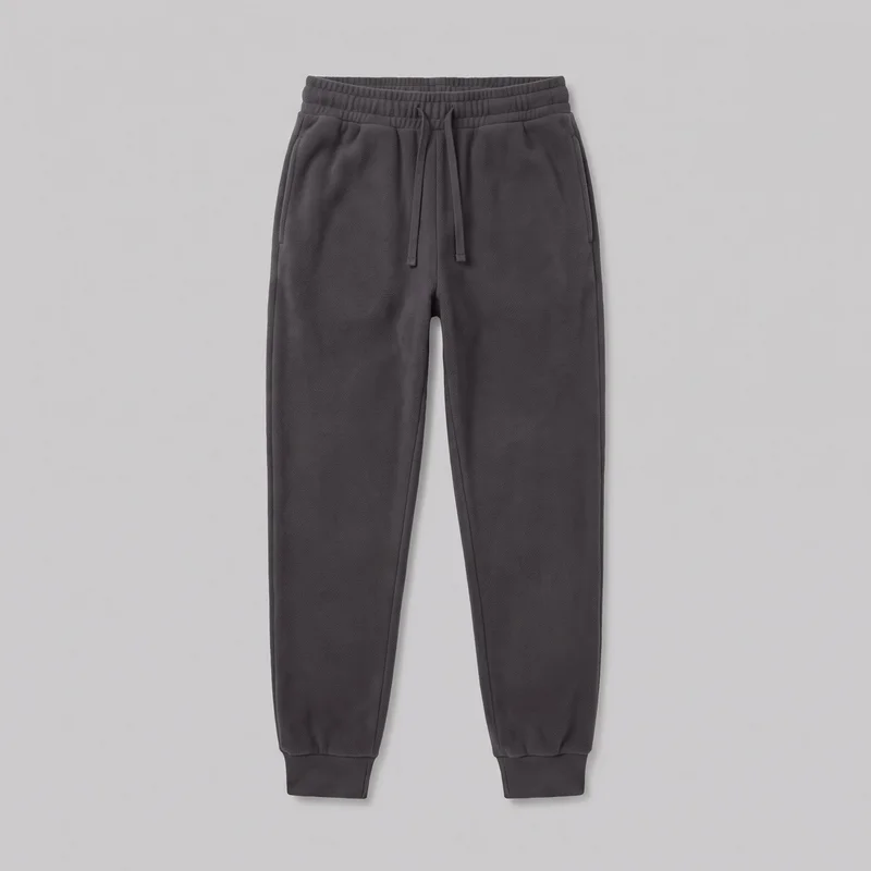 Women's charcoal fleece jogger sweatpants laid flat in a complete front view. The relaxed-fit, full-length pants have tapered legs, an elasticated waistband with stitched channels and a centered external drawstring, two vertical-entry side pockets, and ribbed ankle cuffs. Front rise, inseam, and side seams are visible, with smooth plain panels and no logos or embellishments.