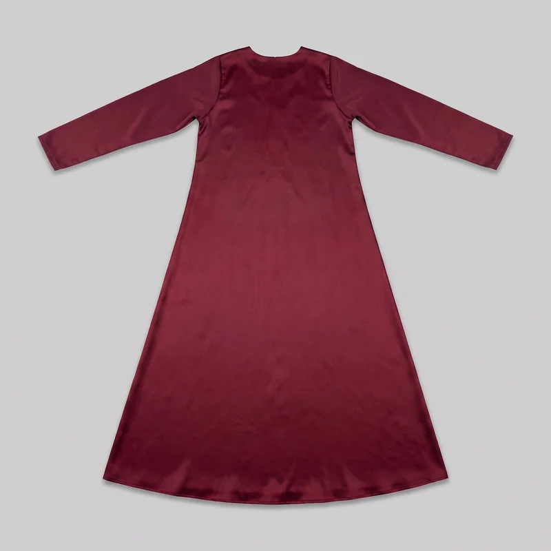 A burgundy satin abaya is shown laid flat from the front. The closed-front design has a shallow round neckline, long straight sleeves with plain cuffs, clean shoulder and curved armhole seams, and a smooth uninterrupted front. Its regular-fit upper body widens into a flared A-line shape that extends to a full-length hem with a gently curved edge.