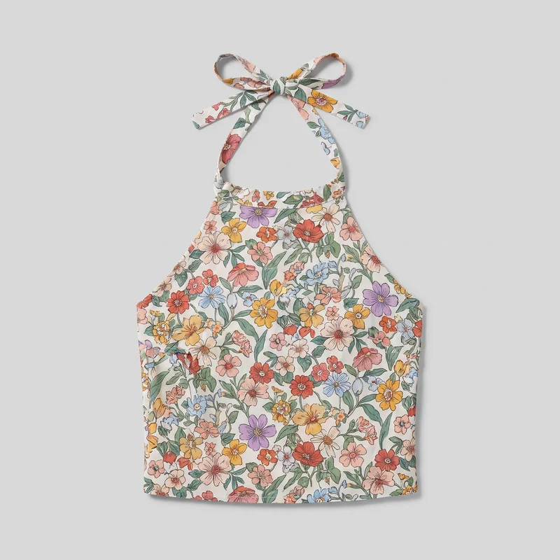 A women's floral print halter top is shown flat in a full front view. It has a wide upper-chest band continuing into narrow halter straps tied at the back neck, open shoulders, curved armholes, a regular fit, visible side seams, and a straight lower hem.