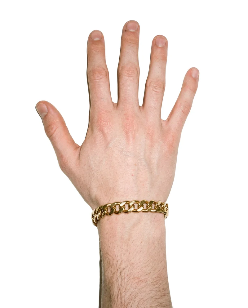 A hand and wrist wearing a men's gold chain bracelet, shown from a top view with the fingers spread. The bracelet is isolated against a pure white backdrop.