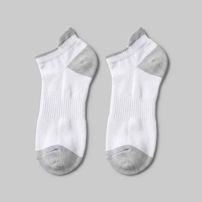 A matching pair of low-cut athletic socks is laid flat and shown from above against a backdrop. The full sock shapes are visible, including rounded closed toes, raised heel tabs, contrasting toe and heel sections, ribbed bands around the midfoot and arch, and textured mesh-knit panels across the upper-foot areas.