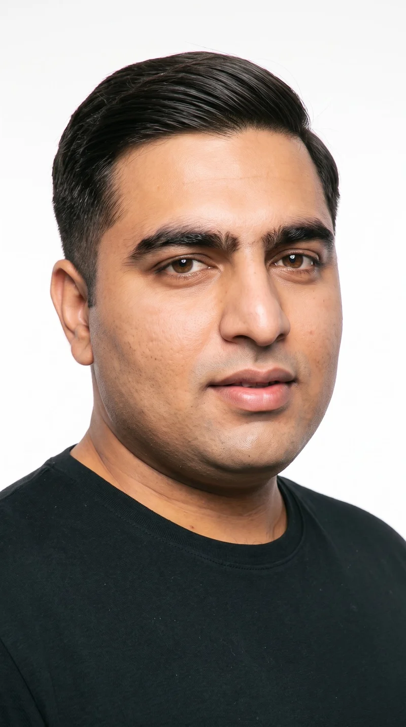 A 31-year-old Indian man with a warm golden undertone to his copper-brown skin and a weathered face with strong definition. He has medium-thick eyebrows, brown eyes, and full lips. His dark-brown hair is combed to one side along a defined part, and his face is clean-shaven.