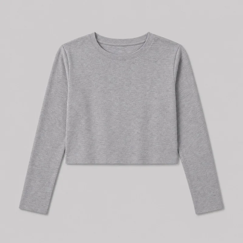 A grey cotton cropped long-sleeve crewneck top is shown in a mostly complete front flat-lay view. It has a slightly boxy silhouette, rounded neckline with a stitched bound neckband, set-in sleeves with finished cuffs, visible shoulder and side seams, and a straight cropped hem. No logos, prints, patches, embroidery, or embellishments are visible.