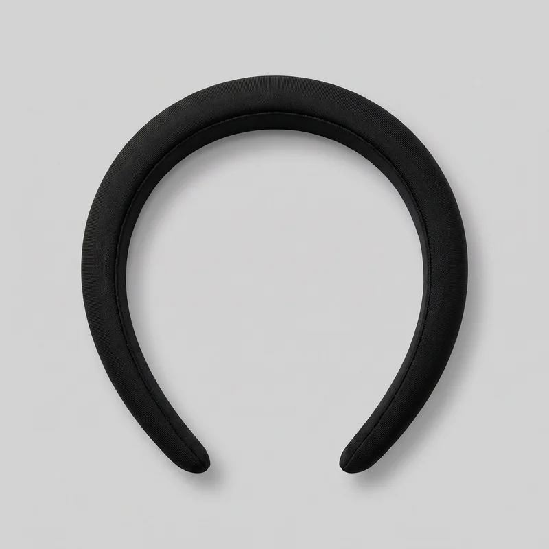 A complete black fabric-covered padded headband is shown from above against a backdrop. Its U-shaped open band has a rounded arched top, tapered arms with rounded tips, and a raised cushioned profile. Fine woven texture and neat seam or piping lines follow the inner channel, with no visible closures, logos, prints, or embellishments.