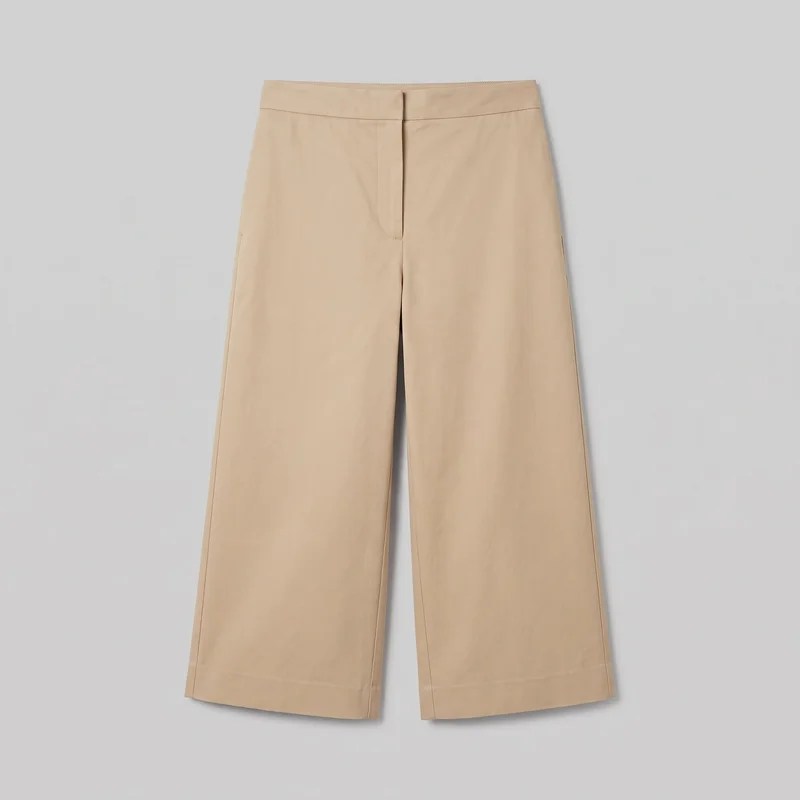 Beige tailored women's culottes laid flat in a standalone front view. They feature a high-rise flat waistband, concealed front fly, relaxed wide legs, visible vertical side seams, curved fly topstitching, and straight calf-length hems ending well above the ankles.