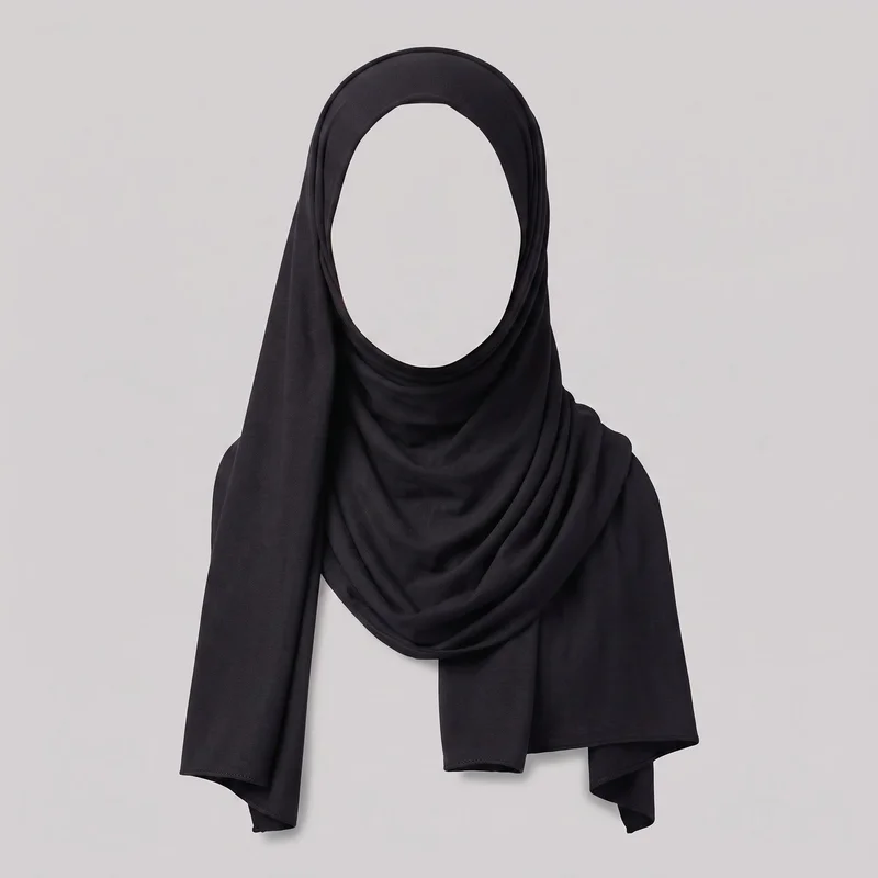 A black jersey hijab is wrapped on a visible head-and-shoulder display form. The front view shows the close-fitting oval face opening, smooth rounded crown framing, overlapping folds around the neck, and layered side panels draped over the shoulders and upper chest with straight-edged, narrow-hemmed ends. No closures, hardware, logos, prints, embroidery, patches, or embellishments are visible.